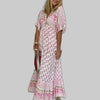 Woman wearing a pink boho maxi dress with all-over floral block print and V-neckline, gray background