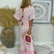 Back view of woman in pink boho maxi dress showing all-over floral block print and border hem detailing