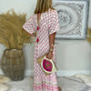 Back view of woman in pink boho maxi dress showing all-over floral block print and border hem detailing