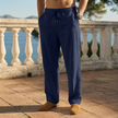 Man wearing navy blue linen drawstring pants standing on a terrace