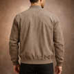 Close-up detail of men's beige bomber jacket collar and front zip