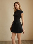 Side view of a woman wearing a black mini dress with flap hip pocket detail