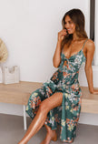 Woman smiling in a green floral maxi dress with cutout waist detail