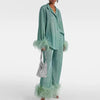 Woman wearing a shimmering light green pants set with feather trim cuffs and hems