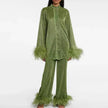 Woman wearing a shimmering dark green pants set with feather trim cuffs and hems