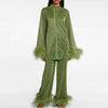 Woman wearing a shimmering dark green pants set with feather trim cuffs and hems