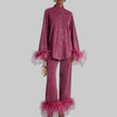 Woman wearing a shimmering wine red pants set with feather trim cuffs and hems