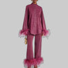 Woman wearing a shimmering wine red pants set with feather trim cuffs and hems