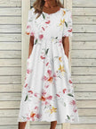 Woman wearing a white midi dress with soft pink and yellow watercolor floral print and short sleeves