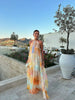 Woman standing outdoors wearing a flowing watercolor print halter maxi dress