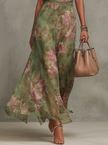 Close-up of the flowing floral maxi skirt with a woman holding a beige handbag
