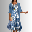 Model wearing blue layered midi set with sheer chiffon duster cardigan and white floral print slip dress, styled with jewelry