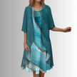 Model in teal layered midi set with sheer cardigan over abstract marble-pattern slip dress with gold diagonal stripe detail