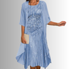 Woman in light blue elegant layered midi set with sheer chiffon cardigan and sequin-embellished slip dress, holding clutch