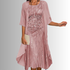 Woman in dusty pink elegant layered midi set with sheer chiffon cardigan and sequin-detailed slip dress, holding clutch