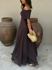 Side view of a woman wearing a brown ruched off-shoulder maxi dress