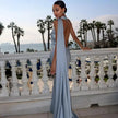 Back view of a woman wearing a light blue one-shoulder evening gown with an open back