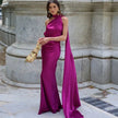 Woman wearing a magenta purple one-shoulder evening gown with a draped sash