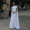Woman wearing a white one-shoulder evening gown with a draped trailing sash