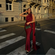 Woman wearing a wine red one-shoulder evening gown standing on a street