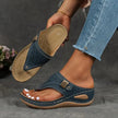 Blue wedge sandal with laser-cut strap held up by hand