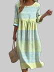 Woman wearing a yellow and blue checkered plaid midi dress, holding a woven straw bag