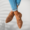 Woman crossing ankles wearing brown suede pointed-toe loafers