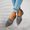 Woman's feet dangling in gray suede pointed-toe penny loafers