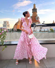 Woman wearing a pink cherry blossom print maxi dress with ruffled straps on a rooftop terrace