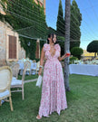 Woman wearing a pink floral maxi dress with ruffled shoulder straps at an outdoor garden event