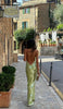 Back view of a woman wearing a green sequin maxi dress with an open back and crisscross straps