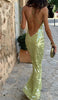 Woman walking away wearing a green sequin maxi dress with a low open back