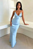 Woman sitting wearing a light blue satin slip dress with a deep V-neckline