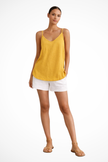 Woman wearing a yellow linen spaghetti strap top with white shorts