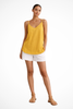 Woman wearing a yellow linen spaghetti strap top with white shorts