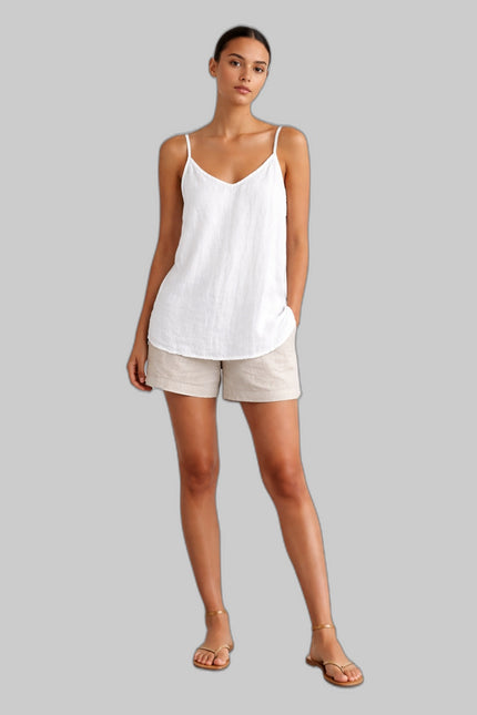 Woman wearing a white linen spaghetti strap top with beige shorts