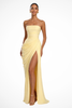 Woman wearing a yellow strapless ruched maxi dress with a thigh slit
