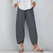 Woman wearing grey wide leg casual pants with asymmetric hem and side pockets, paired with white blouse
